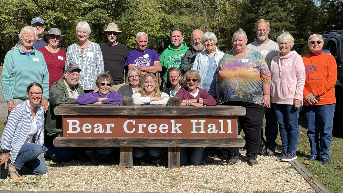Group standing around a sign reading Bear Creek Hall